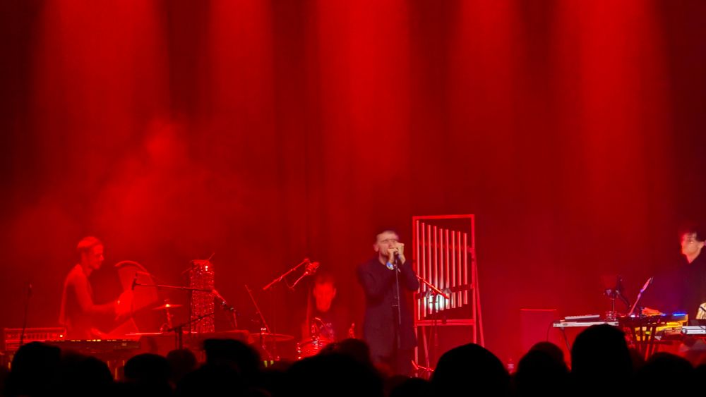 These New Puritans on stage in red light 