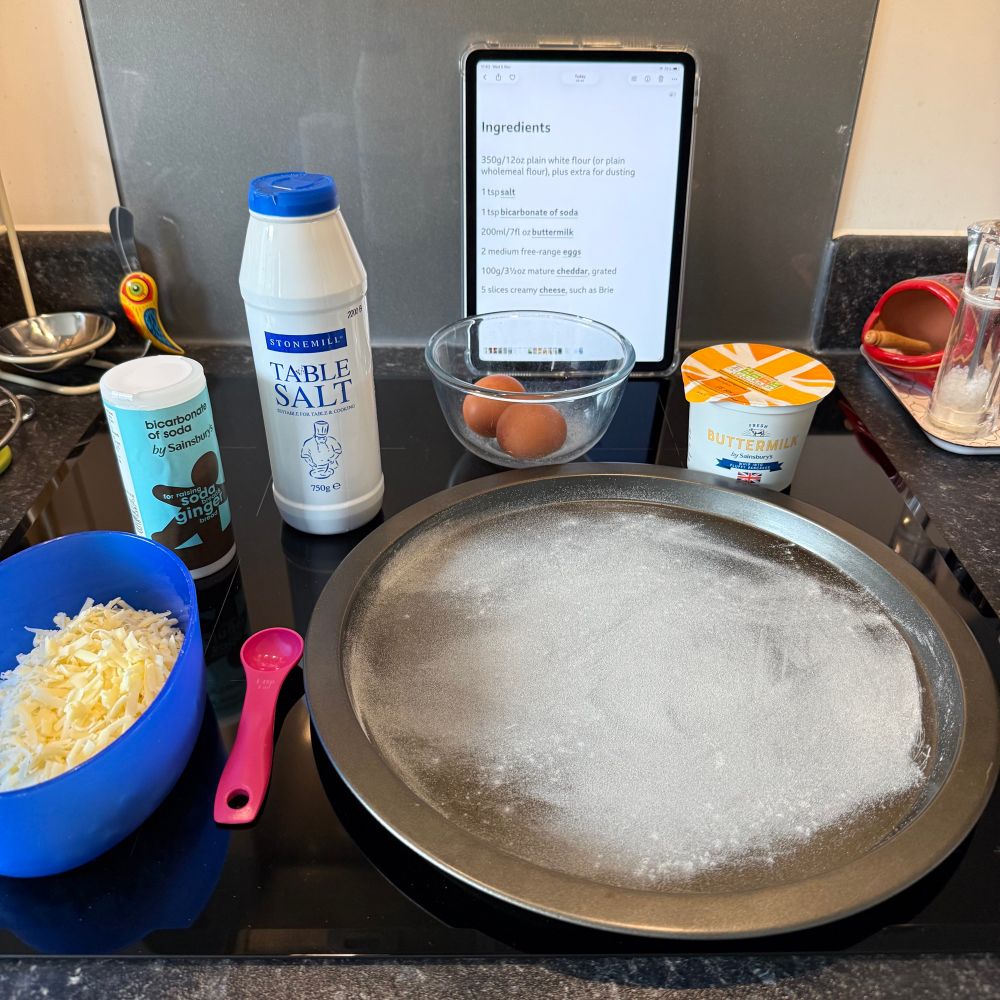 Ingredients for cheesy soda bread: grated cheese, bicarbonate of soda, salt, eggs, buttermilk, oh and there should be flour. There’s a lightly dusted baking tray too.