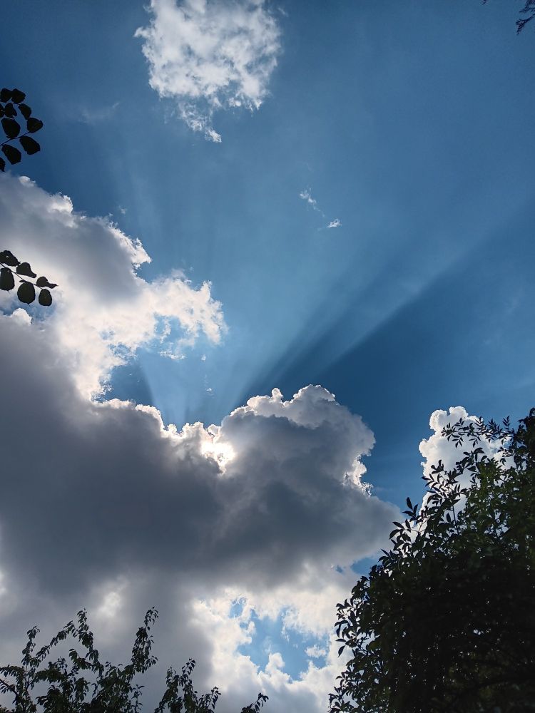 Wolke mit blauem Himmel und Sonnenstrahlen.