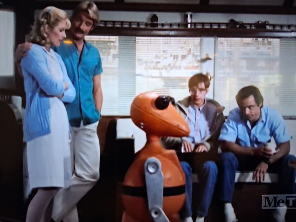 An orange robot and four adults from the 1980s show Riptide 