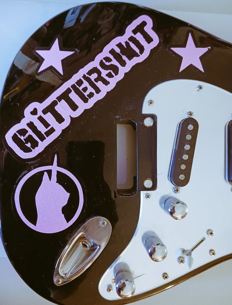 A black Squier Stratocaster with pink decals for the band Glittershot. 