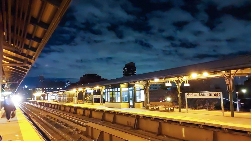 Evening sky over an elevated train station, with the train approaching in the background.