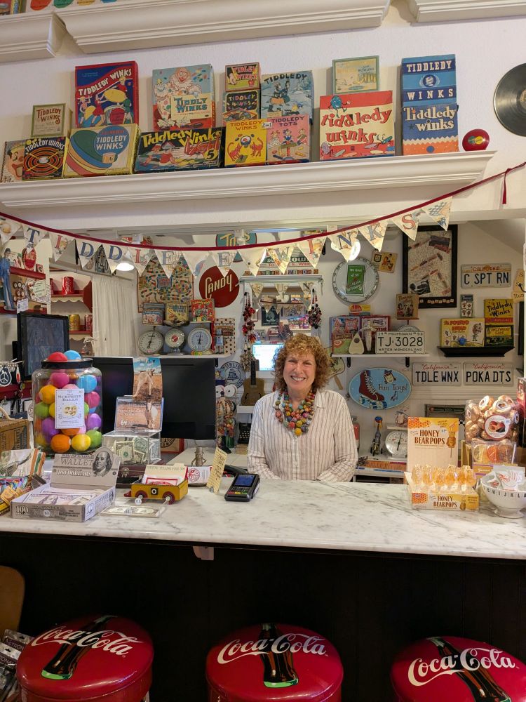 Portrait of the shopkeeper amid a colorful array of vintage goods.