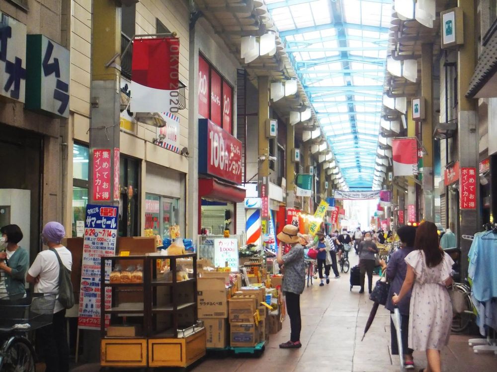 Photo of the Joyful Minowa Shopping Street, in Minowabashi, Tokyo. It looks very similar to the 1979 setting, except there are banners for the Tokyo 2020 Olympics.