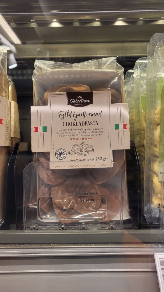 En förpackning brun pasta på en hylla, av märket Ica Selection. Texten på förpackningen lyder "Fylld hjärtformad chokladpasta".