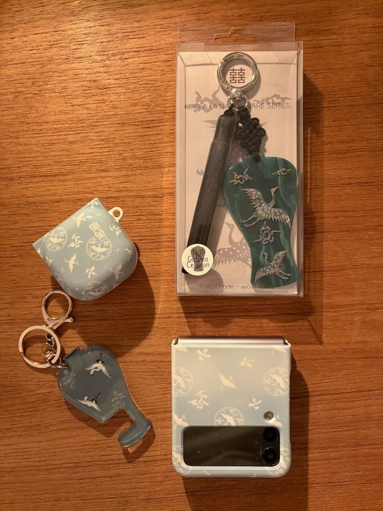 Olika prylar i plast med mönster av klassiskt koreanskt celedon-porslin: två nyckelringar, ett mobilskal och ett hörlursskal.