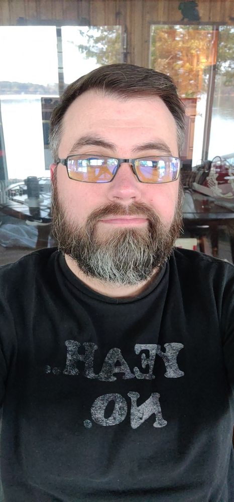 Jon, a nerdy daddy bear, taking a selfie with a black shirt that says "Yeah... No." 