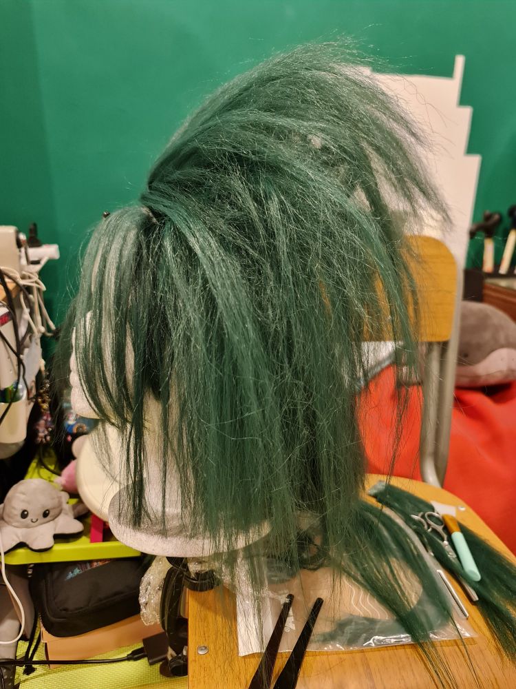 A work in progress photograph of a wig for Orpheus from the 2020 video game Hades, by Supergiant Games. Side view.
