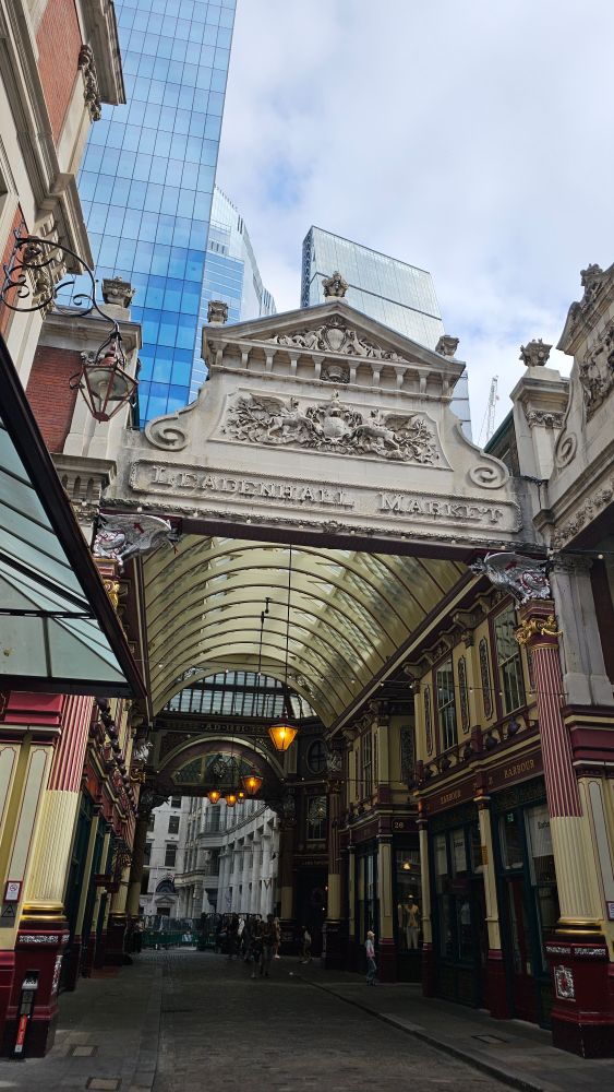 A grand carved stone entrance to a covered glass shopping arcade.