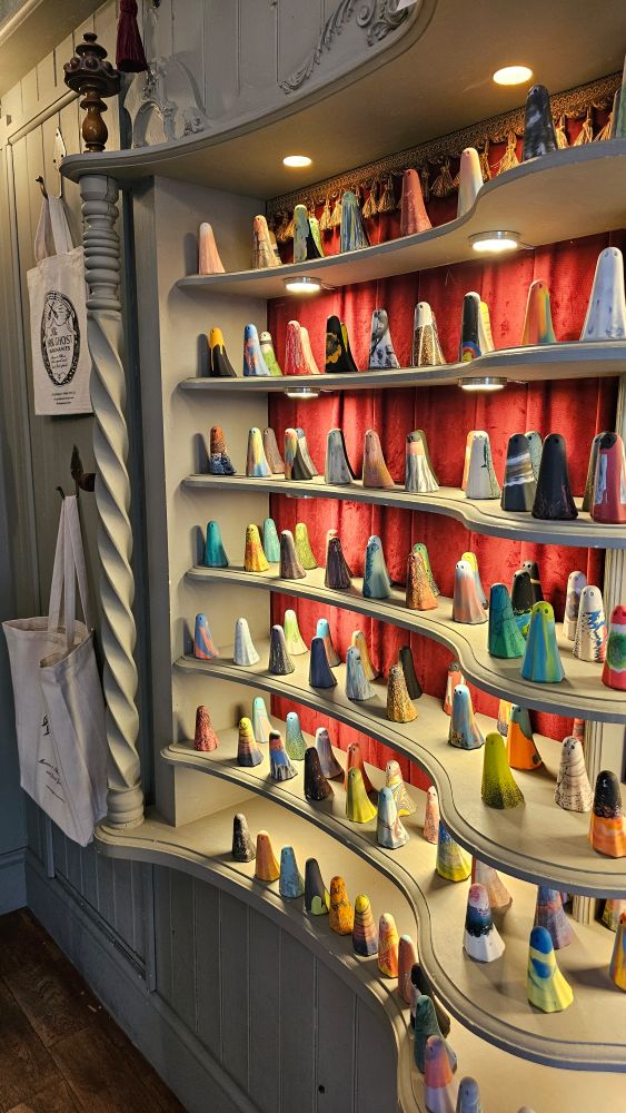Multiple shelves of colourful ghost figures, backed with a red curtain.