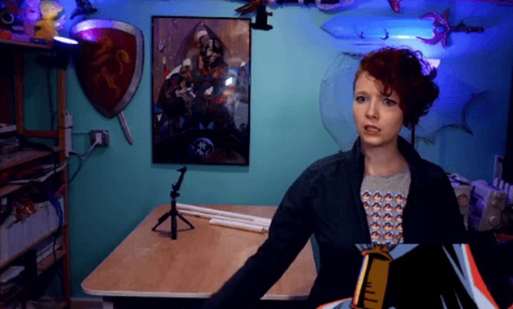 a woman stands in front of a blue wall with a painting on it