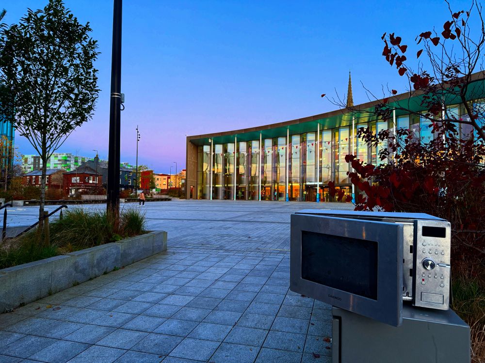 An abandoned microwave in front of the University of Central Lancashire Student Centre in Preston, Lancashire 