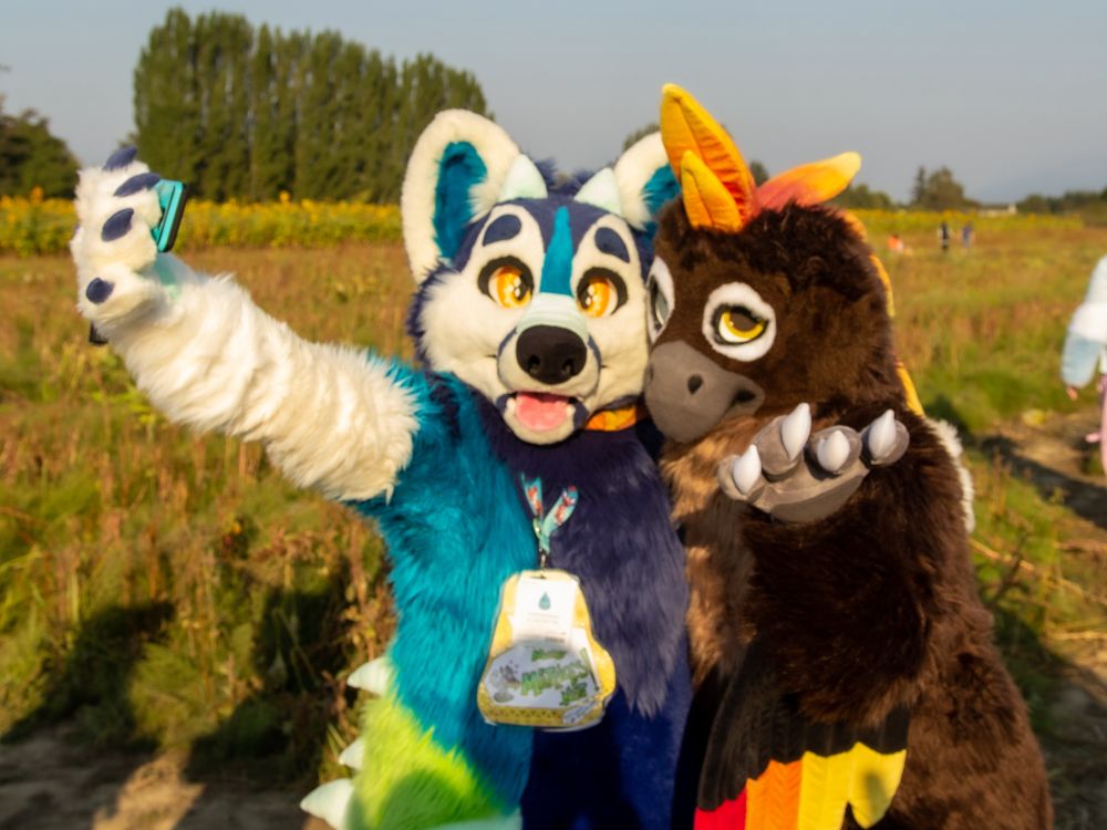 A kaiju dog and phoenix fursuit trying to take a selfie