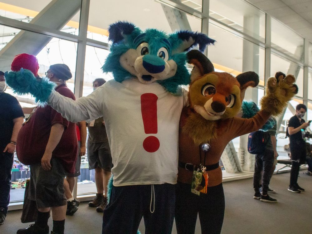 A pair of fursuiters posing together with arms spread. 