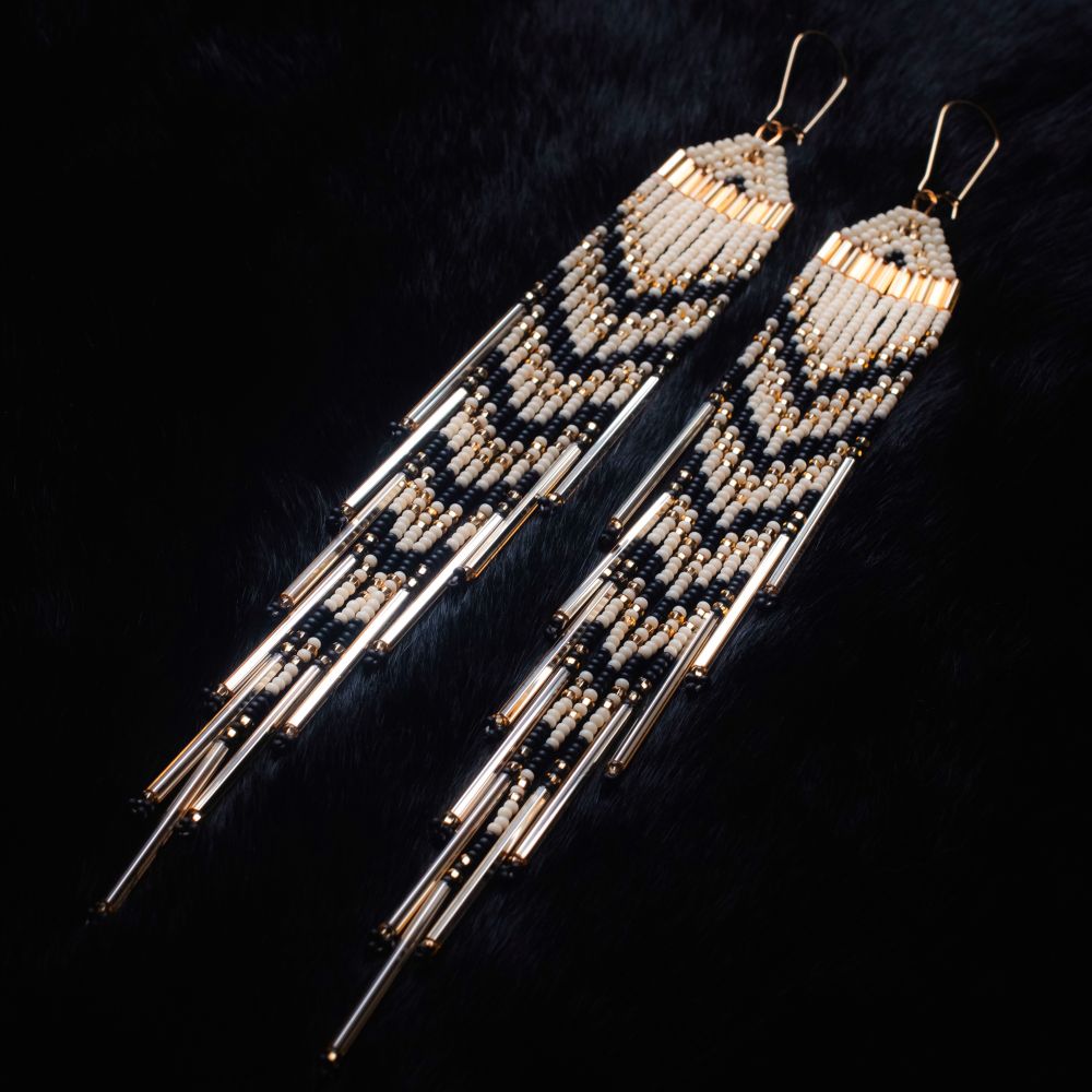 Large beaded fringe earrings. Looks like a waterfall with colours of Ivory, Sparkled with Gold and hardline Black in between ripples. On a black fur backdrop.
