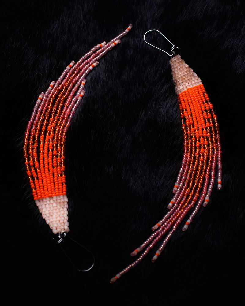 Orange beaded earrings representing for orange shirt day. on a black backdrop