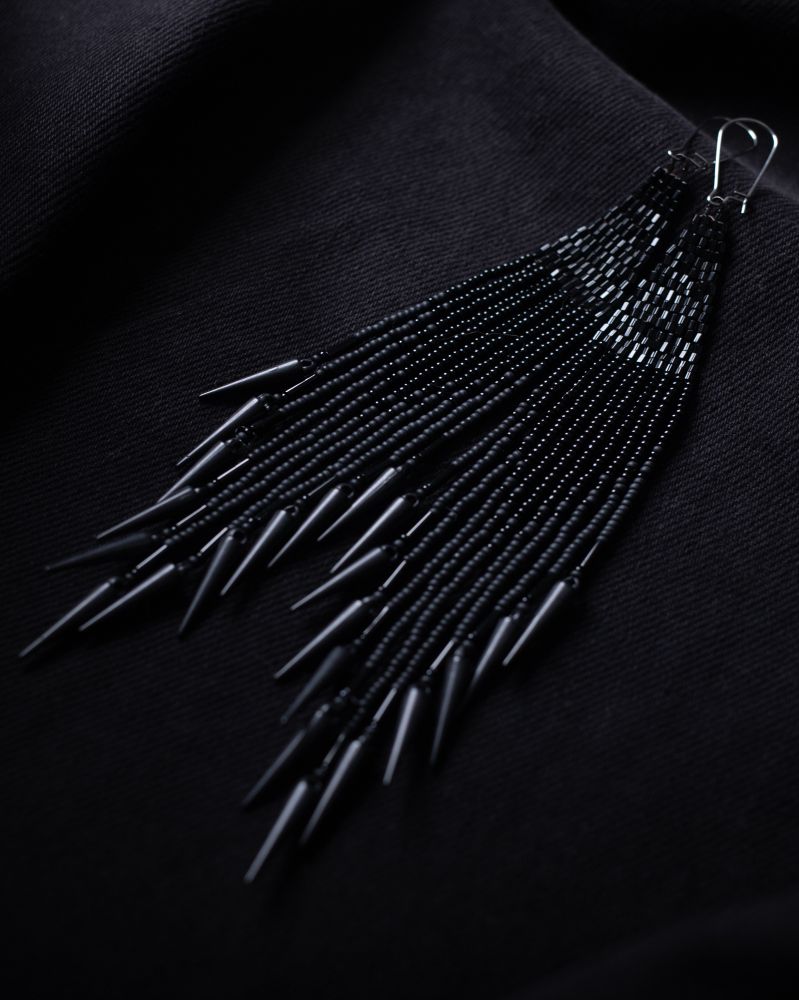 all black beaded earrings, top triangle is shiny, middle beads are shiny black to matte blended. with spikes at the bottom. earrings are on a black jean jacket.