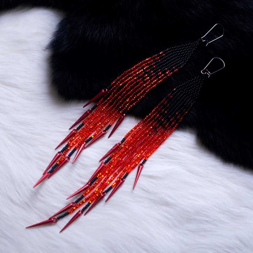 Beaded fringe earrings. Blended from black to orange as a representation of fire. with red spikes. The earrings are on black fur (top half) and white fur (bottom half) to show the sparkle fire effect compared to the top of the earrings