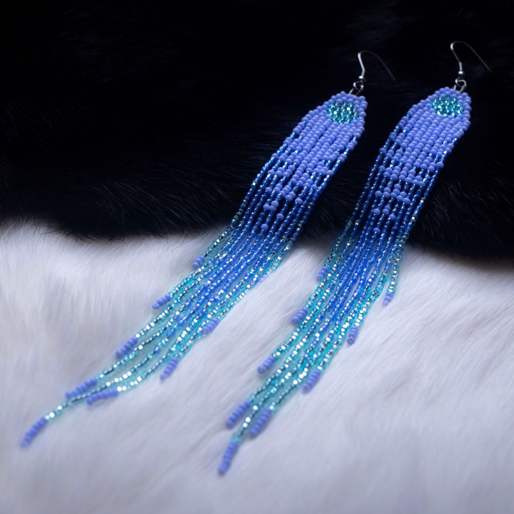 fringe beaded earrings laying on rabbit fur, top half is black fur and bottom is white to show the sparkles. colour palette is powder blue blended into turquoise.