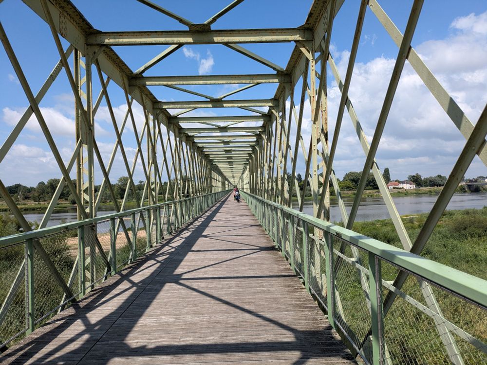 Cycle and pedestrian metal and wood bridge spans a river.