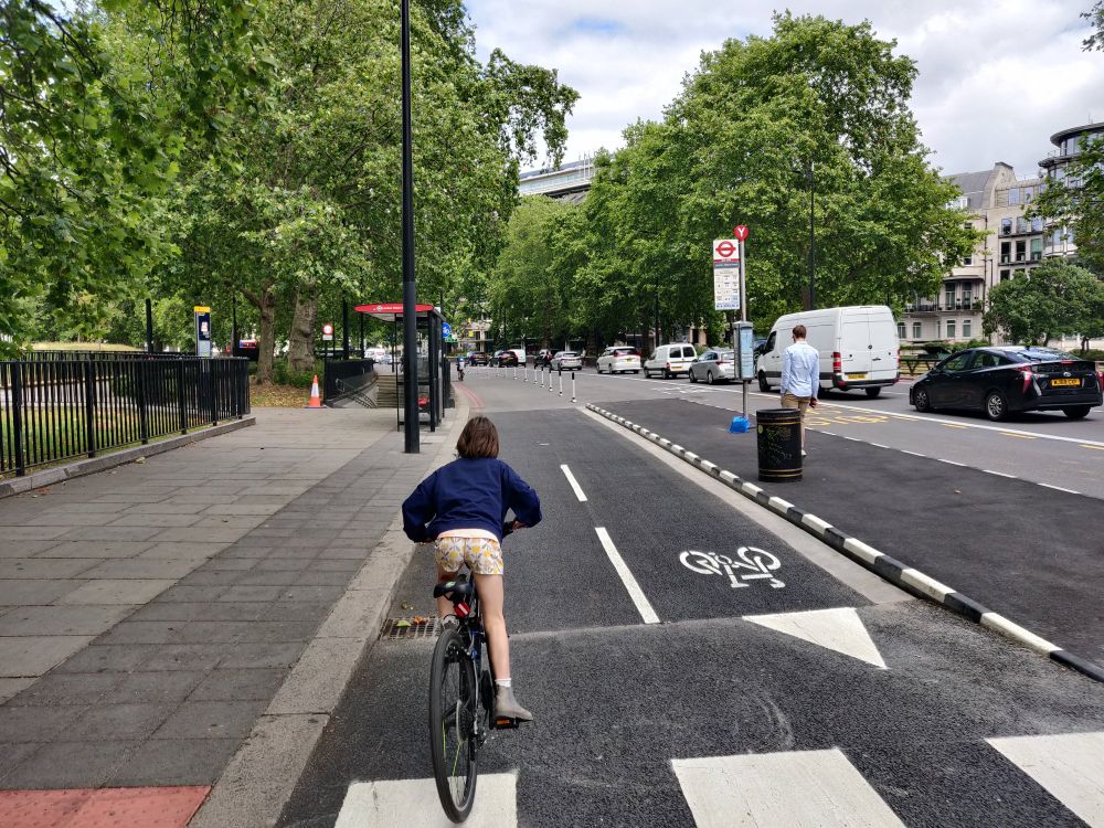Child cycling over a zebra crossing (as no pedestrians are waiting to cross) on a cycle track bus stop bypass.