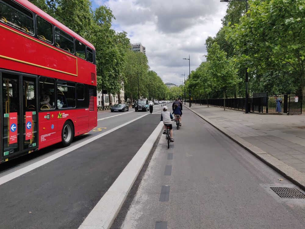 Child cycling on a cycle track past a bus stopped at a bus stop bypass.