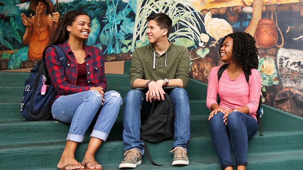 Students sitting on steps in front of a mural at UH Mānoa Campus Center.