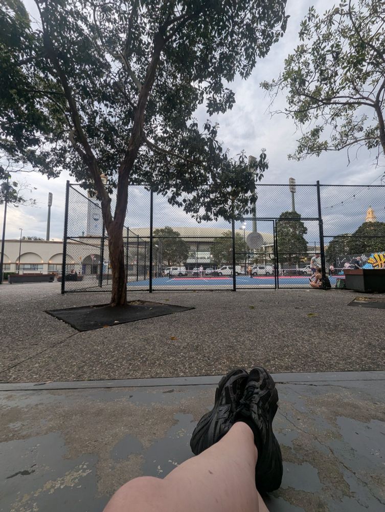 a pickleball court with a pair of legs in foreground 