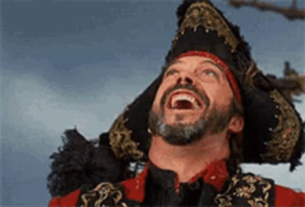 a man with a beard is wearing a pirate costume and laughing .