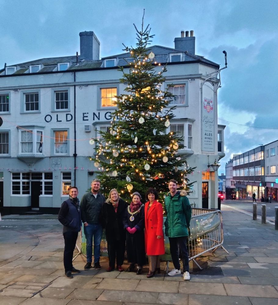 The photo shows Cllrs Glenn Haffenden, Julia Hilton and Becca Horn, Mayor of Hastings, with representatives from Lightning Fibre standing in front of a lit and decorated Christmas the tree in St Leonards.