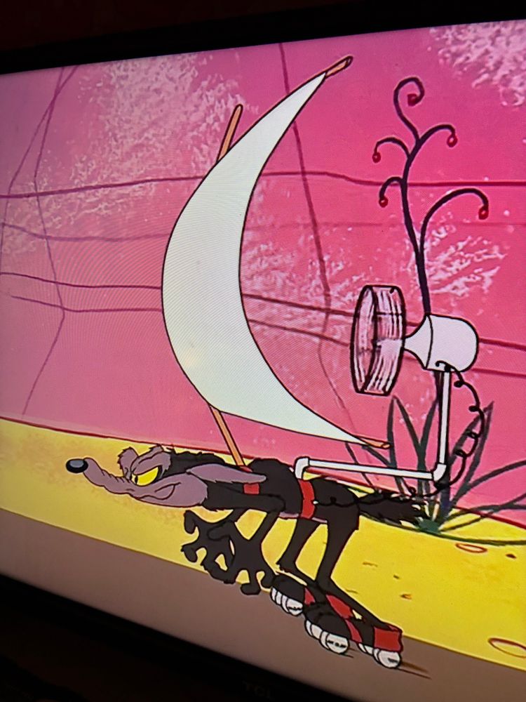 Wile E. Coyote on roller scates wearing a sail powered by a fan 