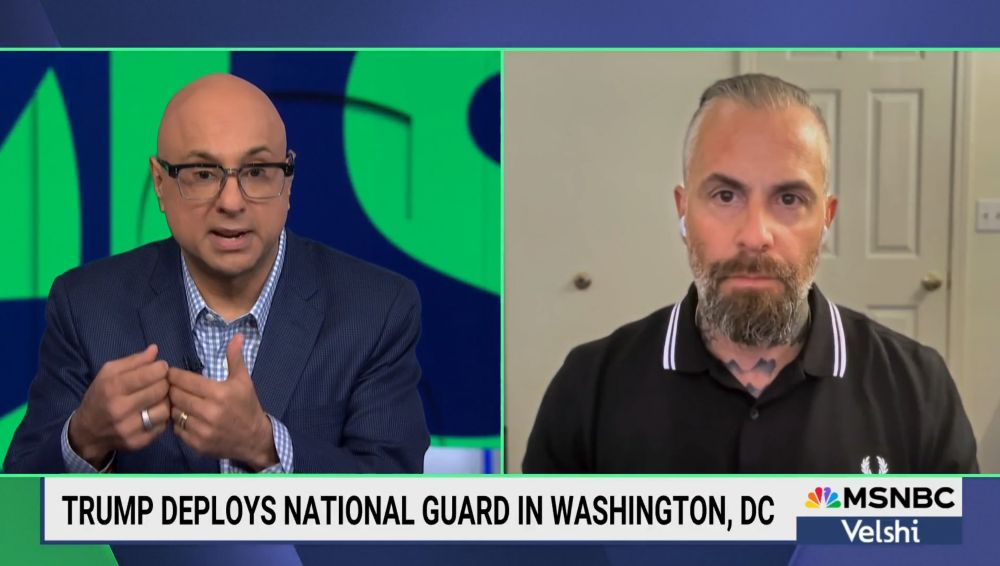 A screenshot of Micheal Fanone interview with Ali Velshi, Fanone is wearing a black Fred Perry shirt with white embroidery