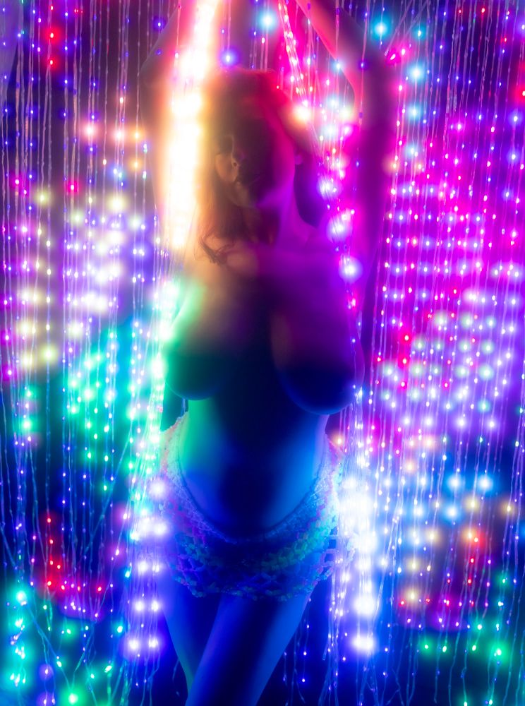 Topless model surrounded by colorful lights