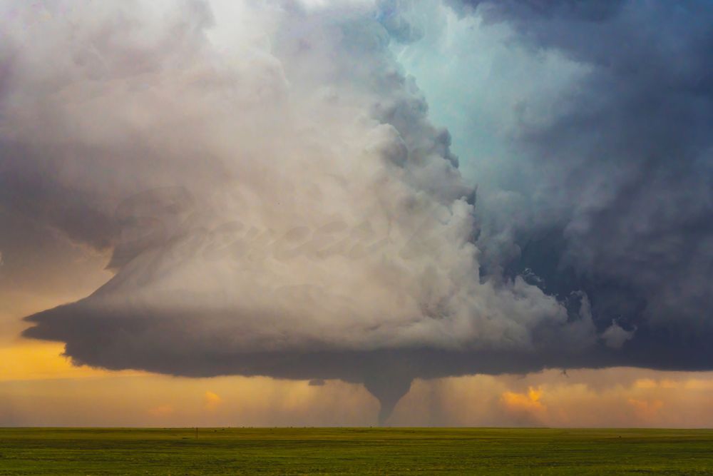 a tornado over open prairie, with a 60,000 foot tall, deep blue colored updraft and downdraft above it