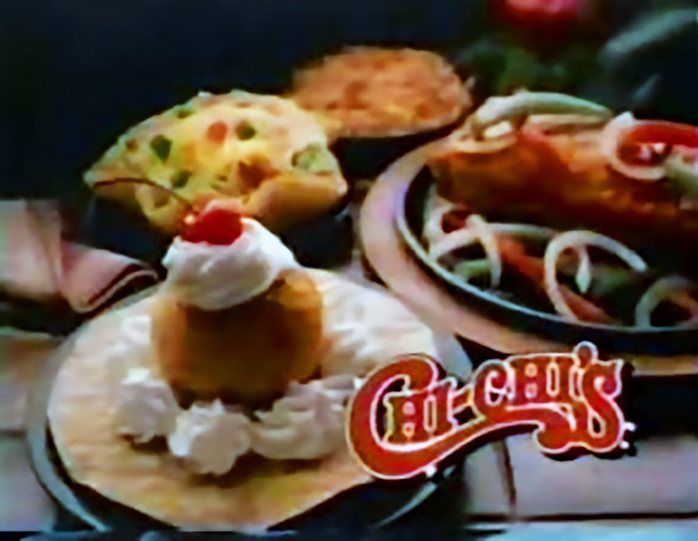 A screenshot from a ChiChi's commercial in the 80s. In the front is a ball of their fried ice cream with dollops of whipped cream and a cherry on top. 