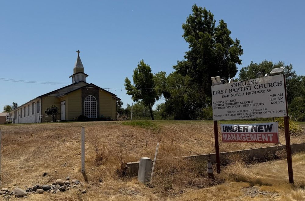 A church with an "under new management" sign in front. 