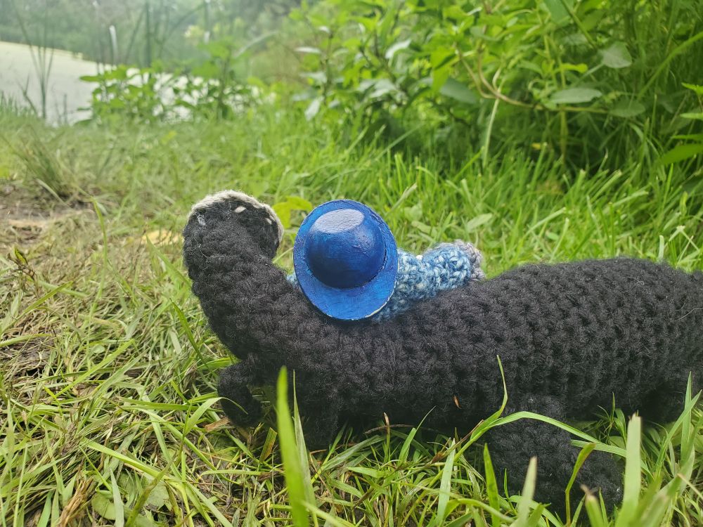A wood doll in crochet dress and a crochet long doll cuddling on the grass