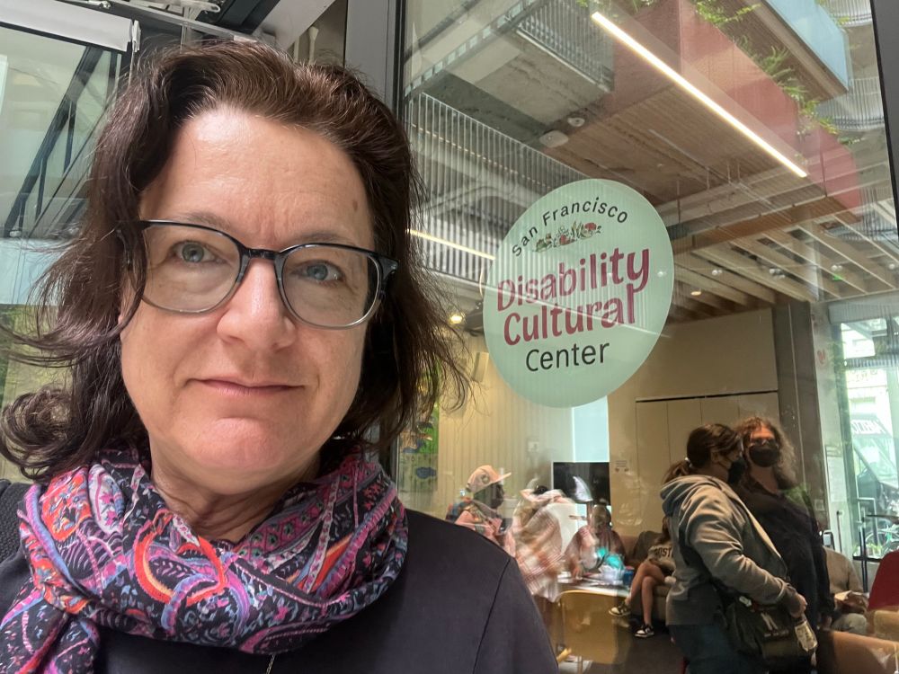 Photo of Claudia Center in front of sign San Francisco Disability Cultural Center