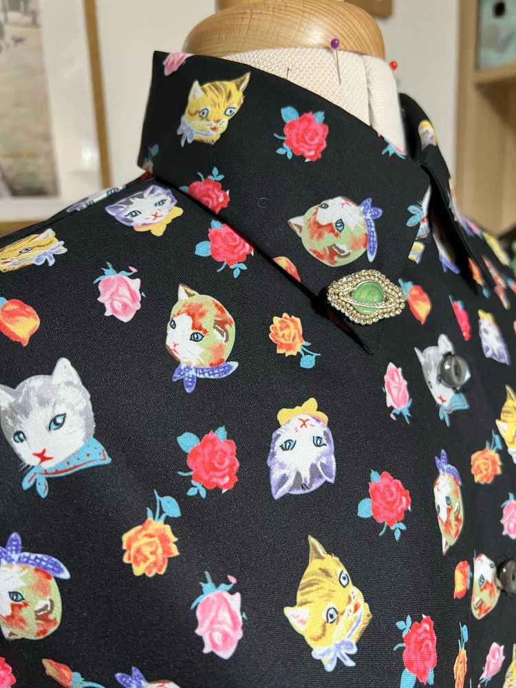 A black shirt with kitschy cats and roses on it. 