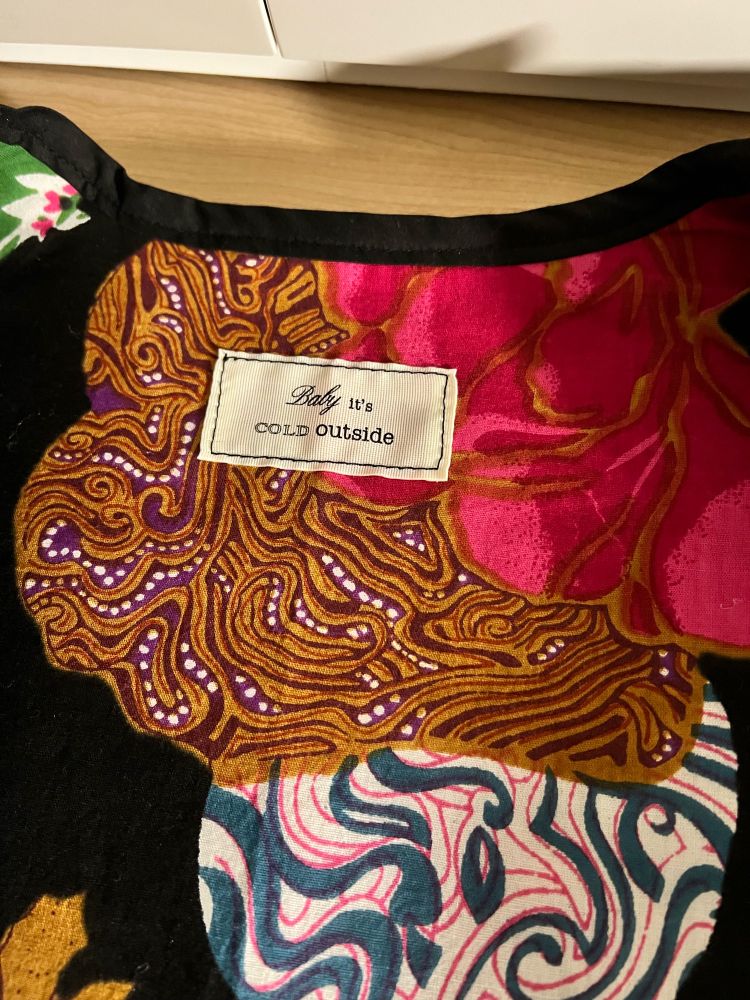 Inside of vest with bright pattern cotton lining and label which says Baby it’s Cold Outside 