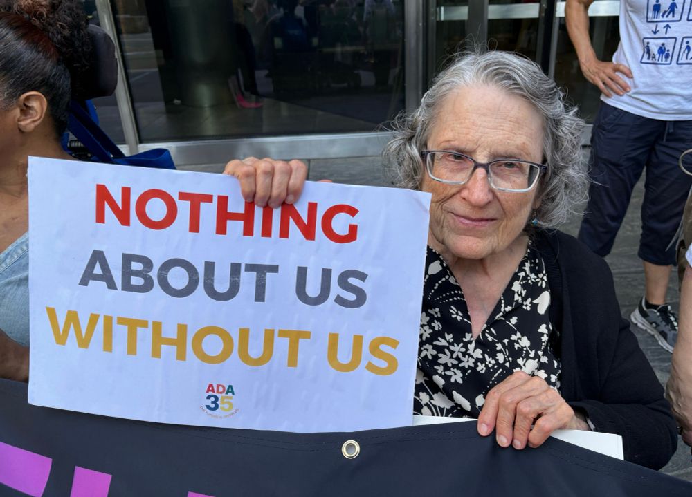 Jean Ryan, president of Disabled In Action, holding a Nothing About Us Without Us protest sign.