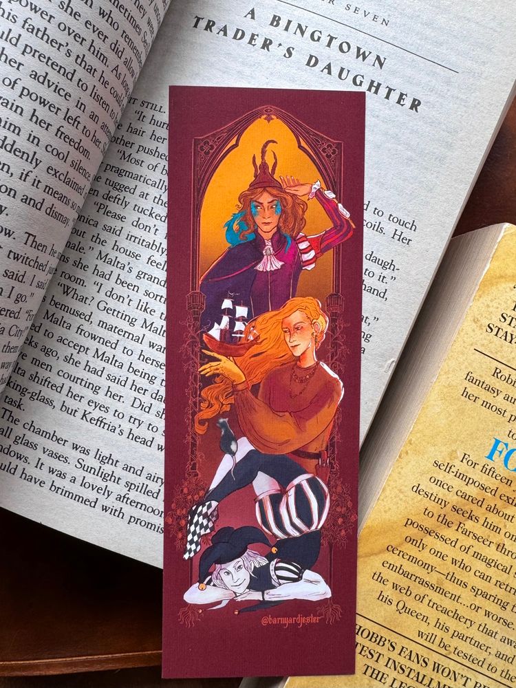A bookmark with art of three versions of The Fool character from Robin Hobb's books.