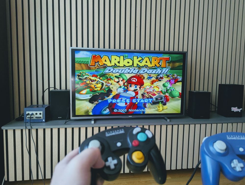 A modern television showing the title screen of Mario Kart: Double Dash