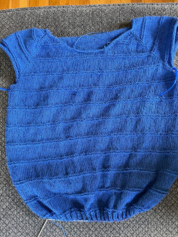 A bright blue knitted top with garter stitch stripes on a silver circular knitting needle. Sleeves & neckline not yet added.