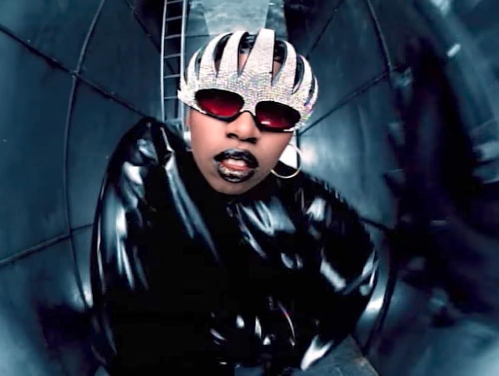Missy Elliott looking at the camera in a small, long room, from the video for The Rain (Supa Dupa Fly)