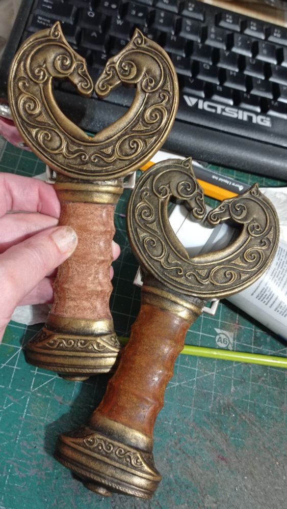 Close pic of the hilt/buckles on my desk, the tones of the metallics closer to the real ones, one more golden and one more bronze