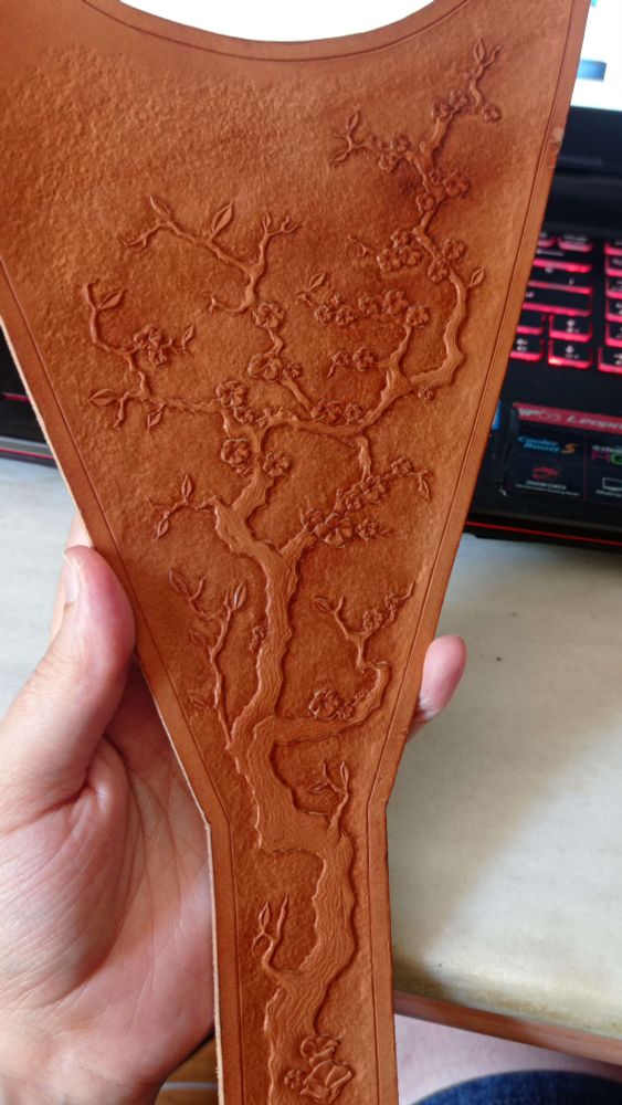 Pic of the triangular piece that will be placed in the front of the cuirass, all the branches and tiny flowers and leaves tooled and textured in detail, and the background tooled with a grainy texture