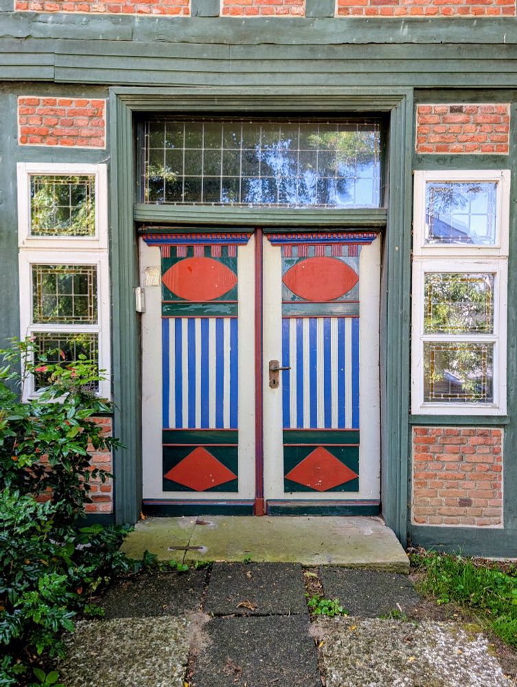 Ein Fachwerkbau mit einer 2flügeligen Tür, die mit farbigen, geometrischen Flächen dekoriert ist.

Hamburg
Vierlande