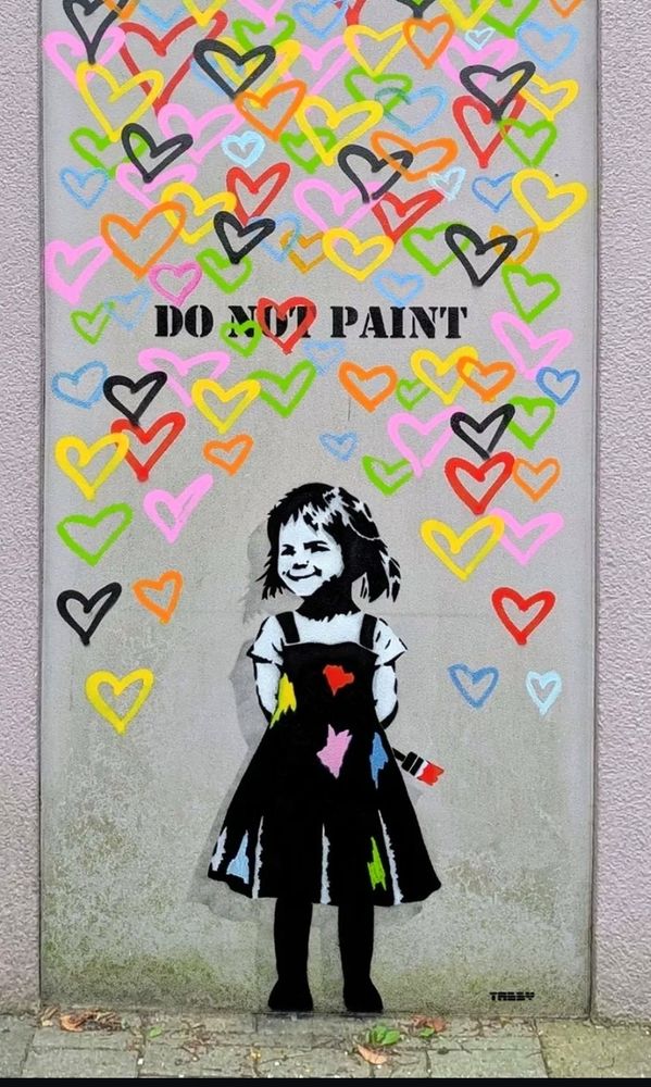 Auf einer hellen Fläche ein Meer an bunten Herzen.
Davor ein kleines Mädchen, in einem Kleid, das einen Pinsel hinter dem Rücken versteckt hält.
Sie schaut verschmitzt.
Über ihrem Kopf steht
DO NOT PAINT.

Das NOT ist kaum erkennbar, da ein Herz darüber gemalt ist.