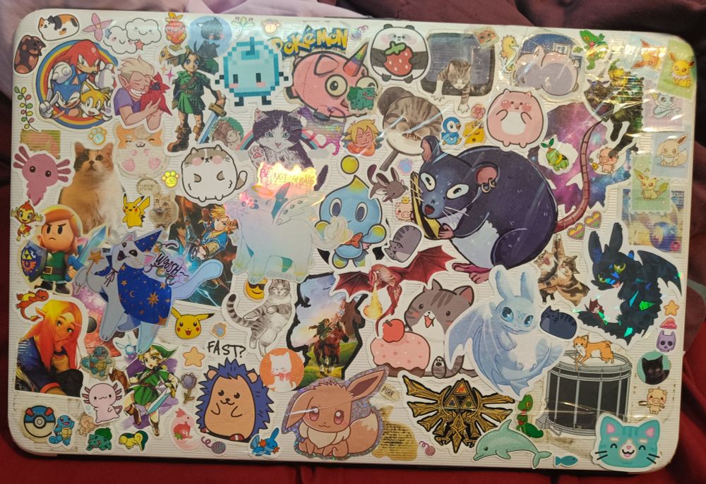 La parte de atrás de mi portátil, llena de un montón de stickers de todo tipo: gatos, ratas, Pokémon, Zelda, axolotl...